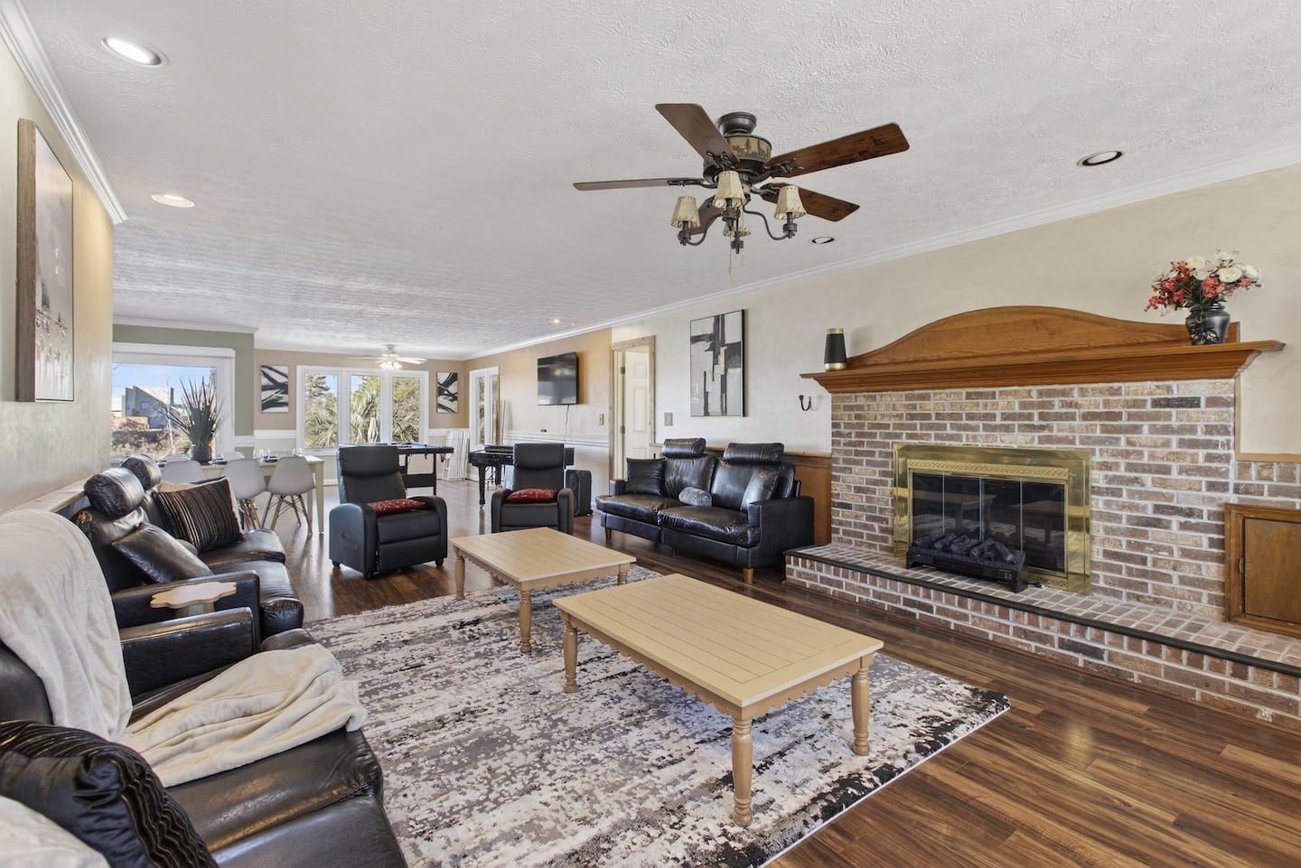 Sofas, a coffee table, ceiling fans, and a brick fireplace in a large living room.
