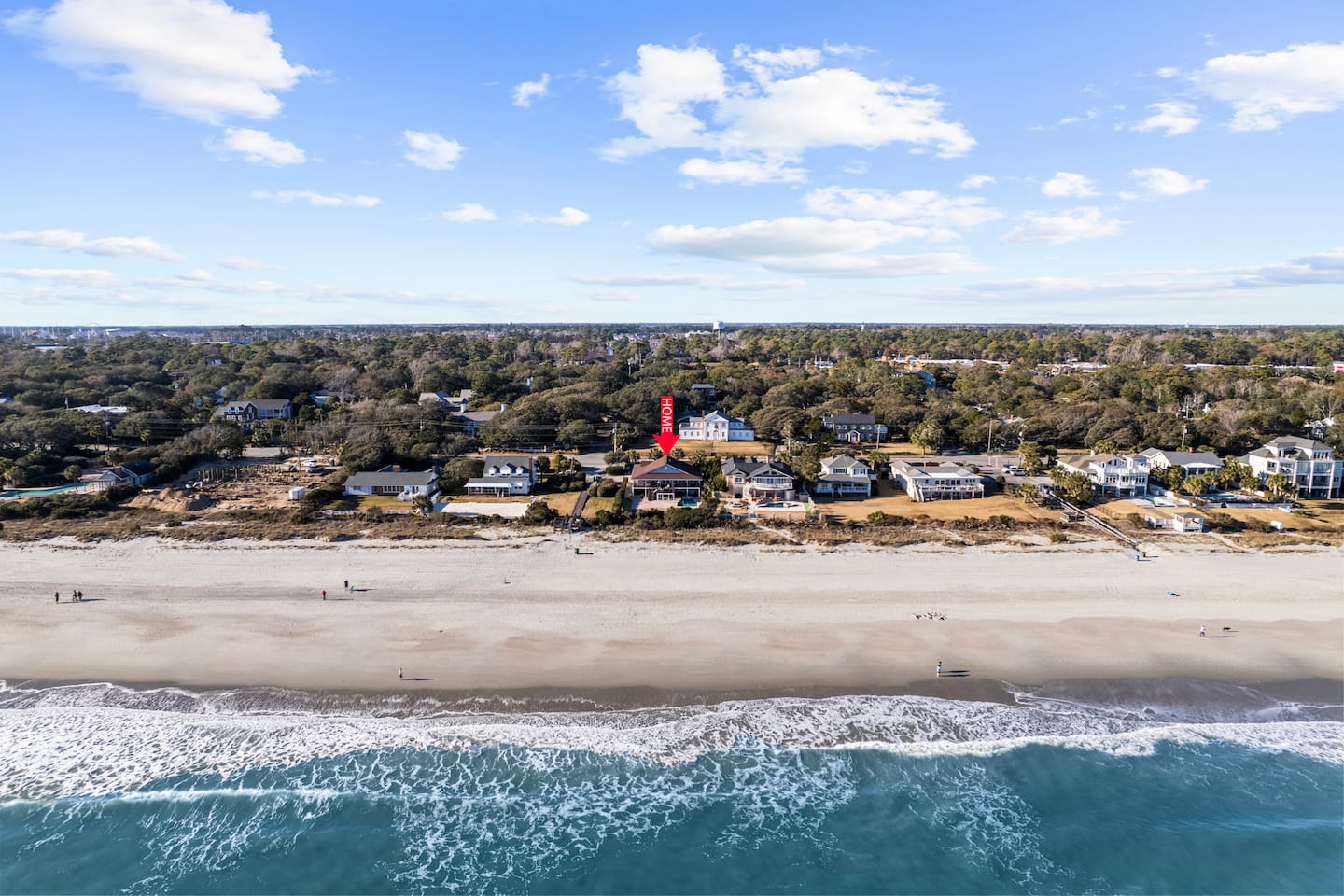 Aerial view of the beach, ocean, and beachfront homes, with a red arrow identifying a listing.
