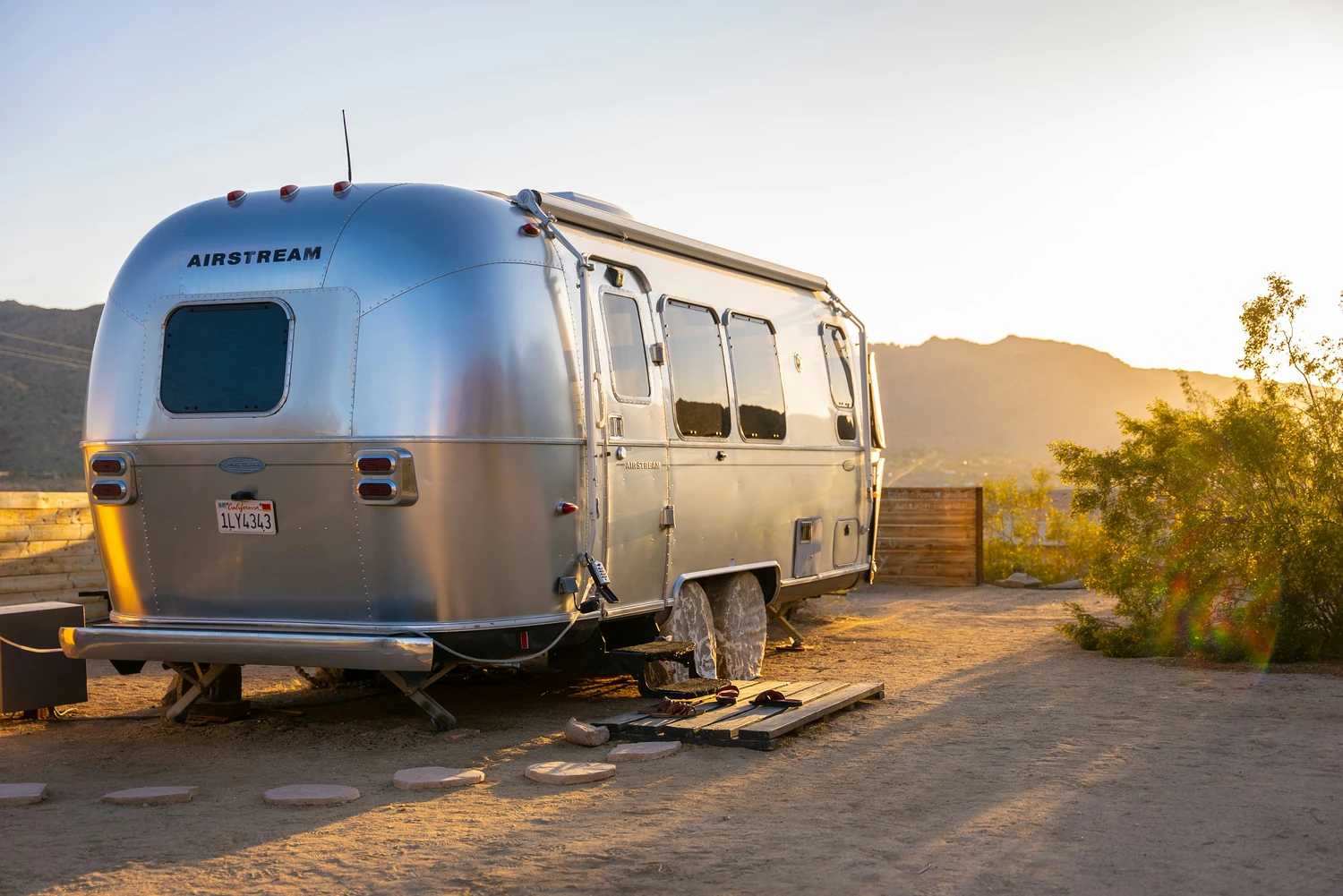 Silver travel trailer parked beside desert hills