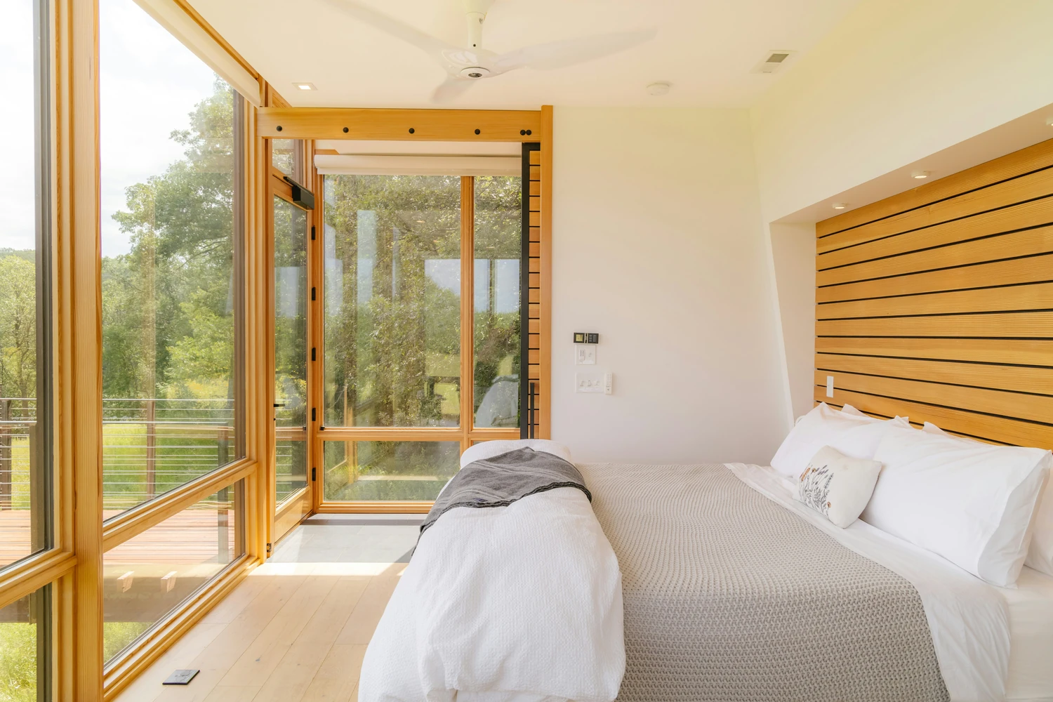 Compact bedroom with an open window overlooking a green landscape