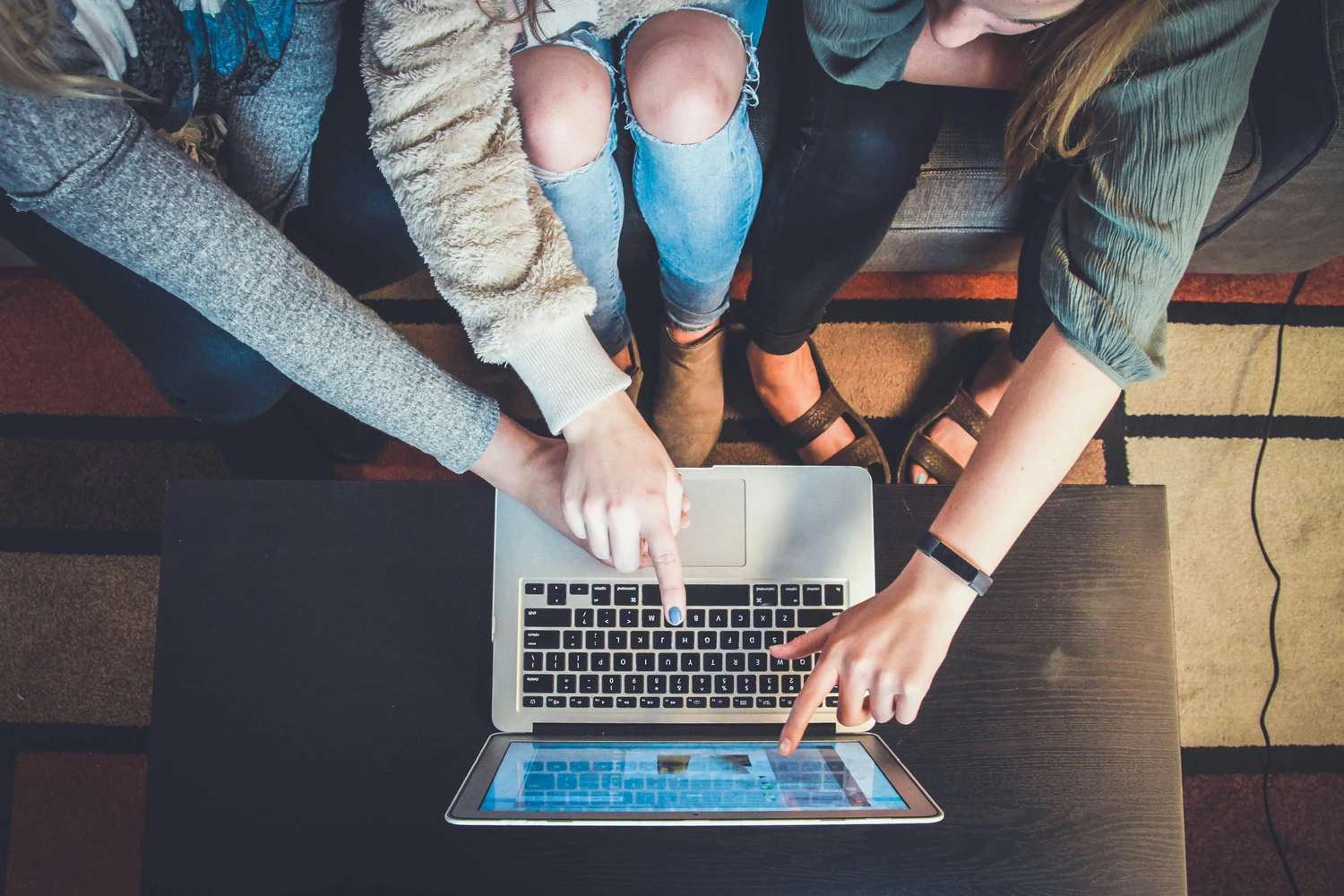 Three coworkers gathered around a laptop