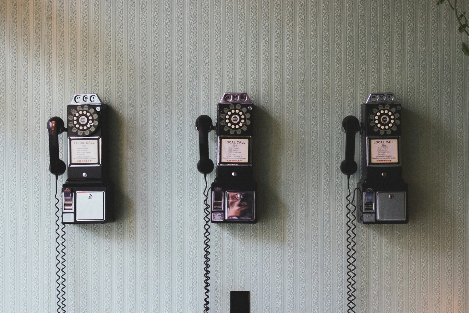 Three wall-mounted payphones in a row