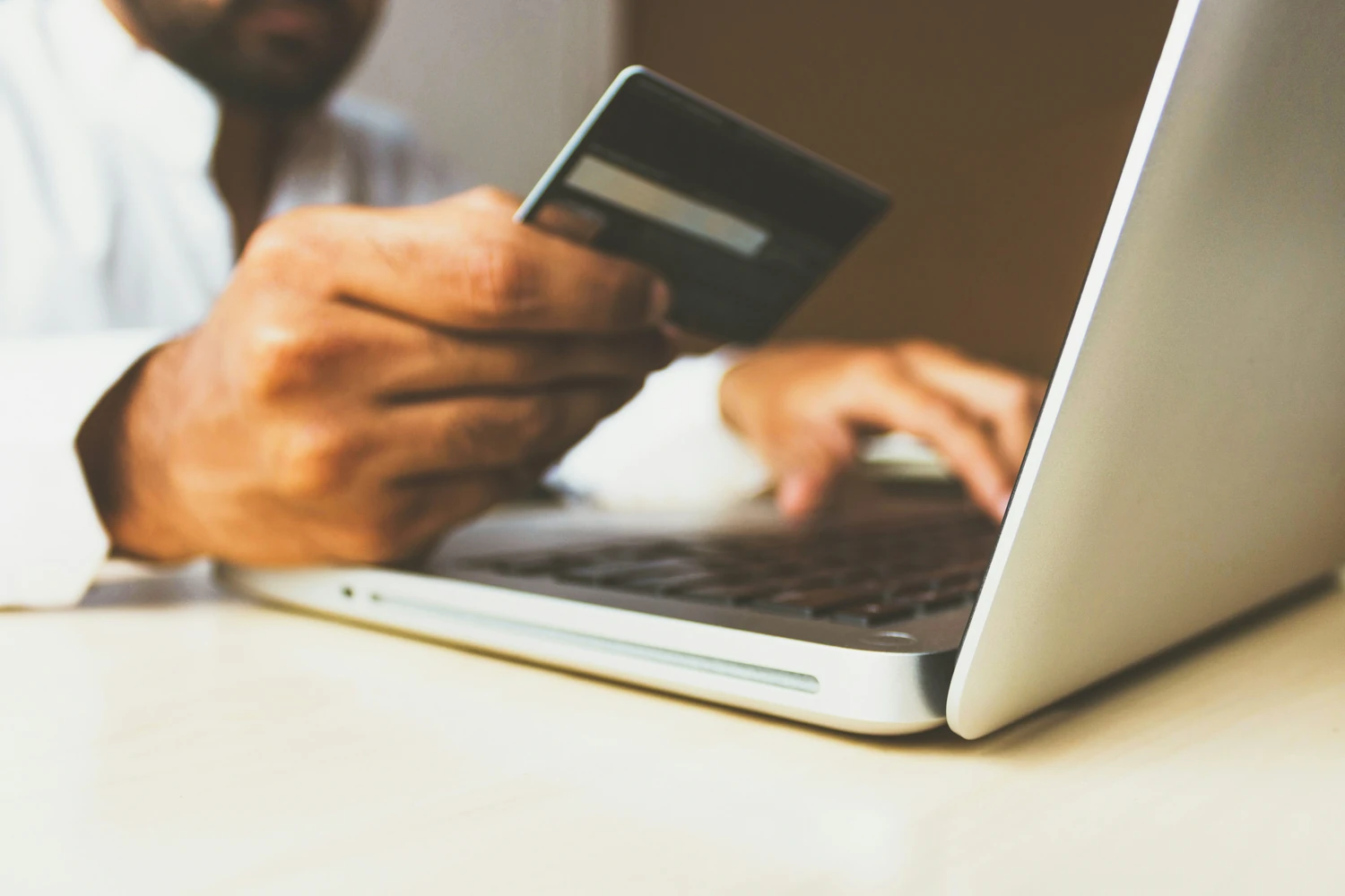 Person holding a payment card while using a laptop