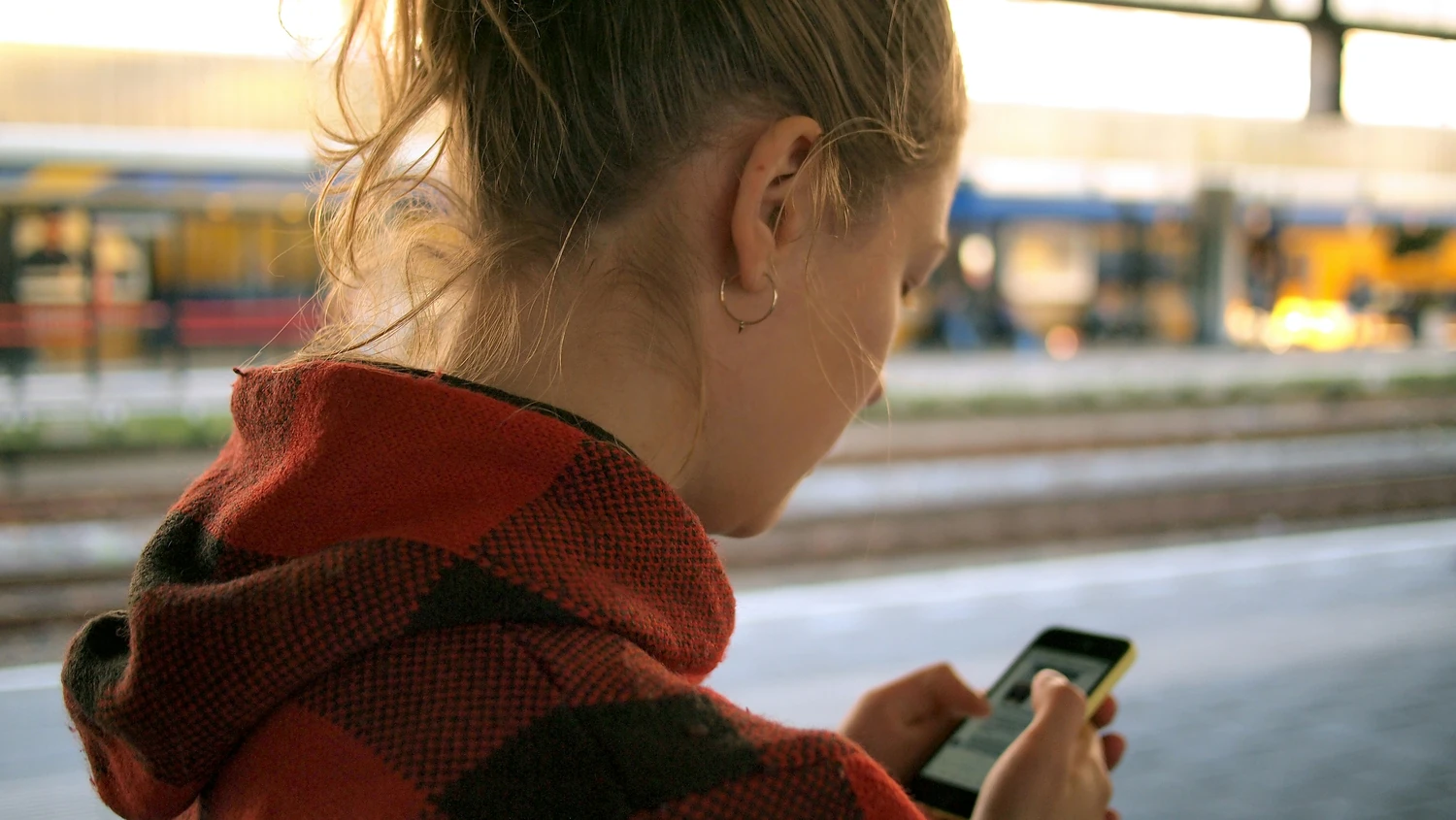 Traveler using a smartphone while waiting at a station