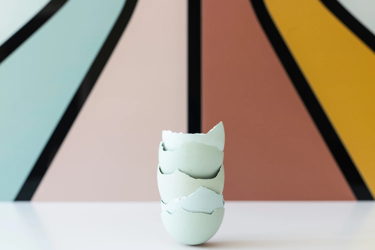White faceted vase in front of a colorful geometric wall