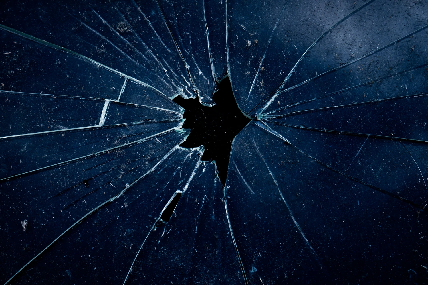Impact hole and radiating cracks in a pane of glass