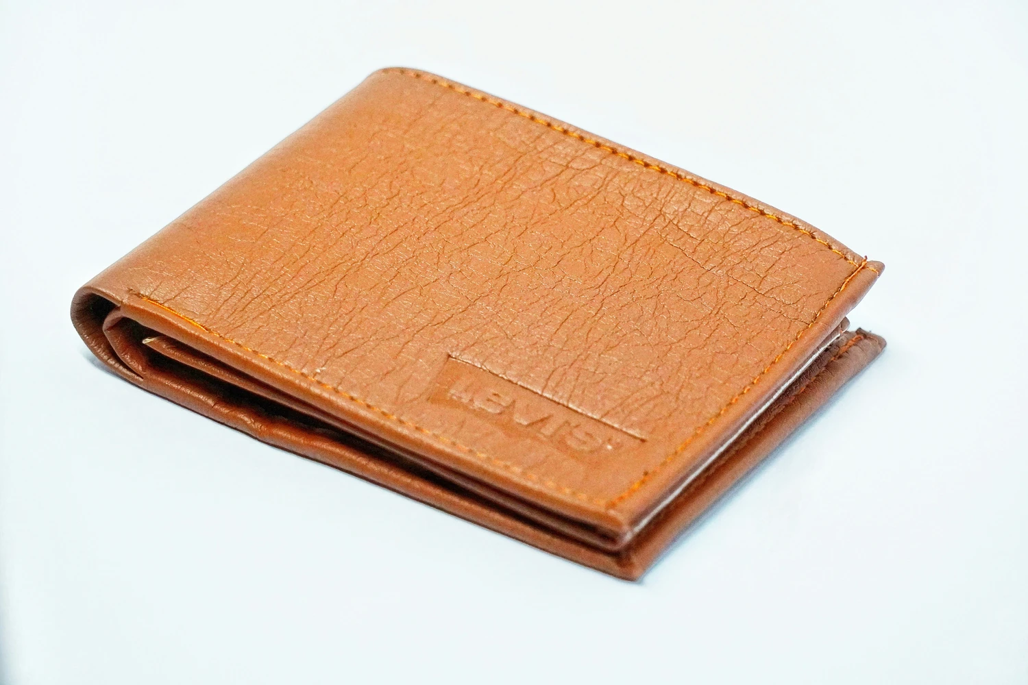 Closed brown leather wallet on a white surface