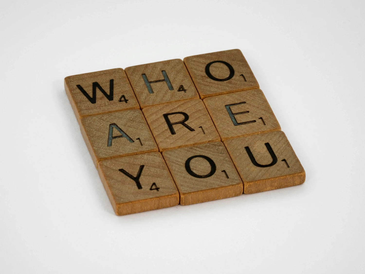 Letter tiles spelling “Who are you?” on a wooden board