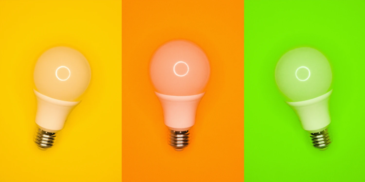 Three light bulbs against yellow, orange, and green backgrounds