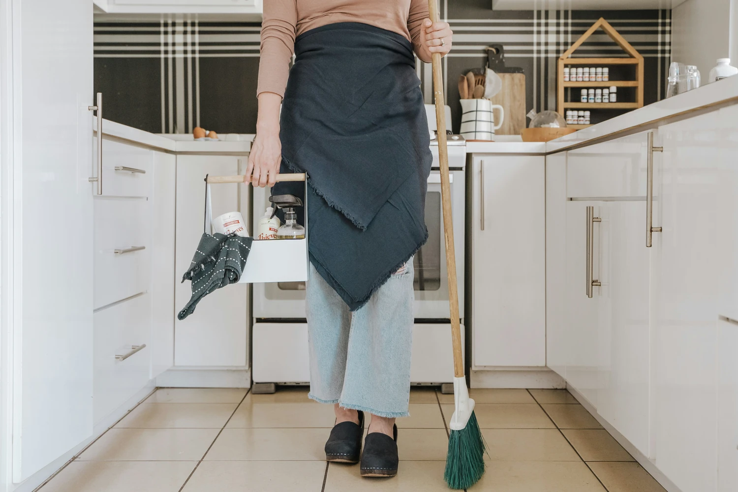 Housekeeper sweeping a bright white kitchen