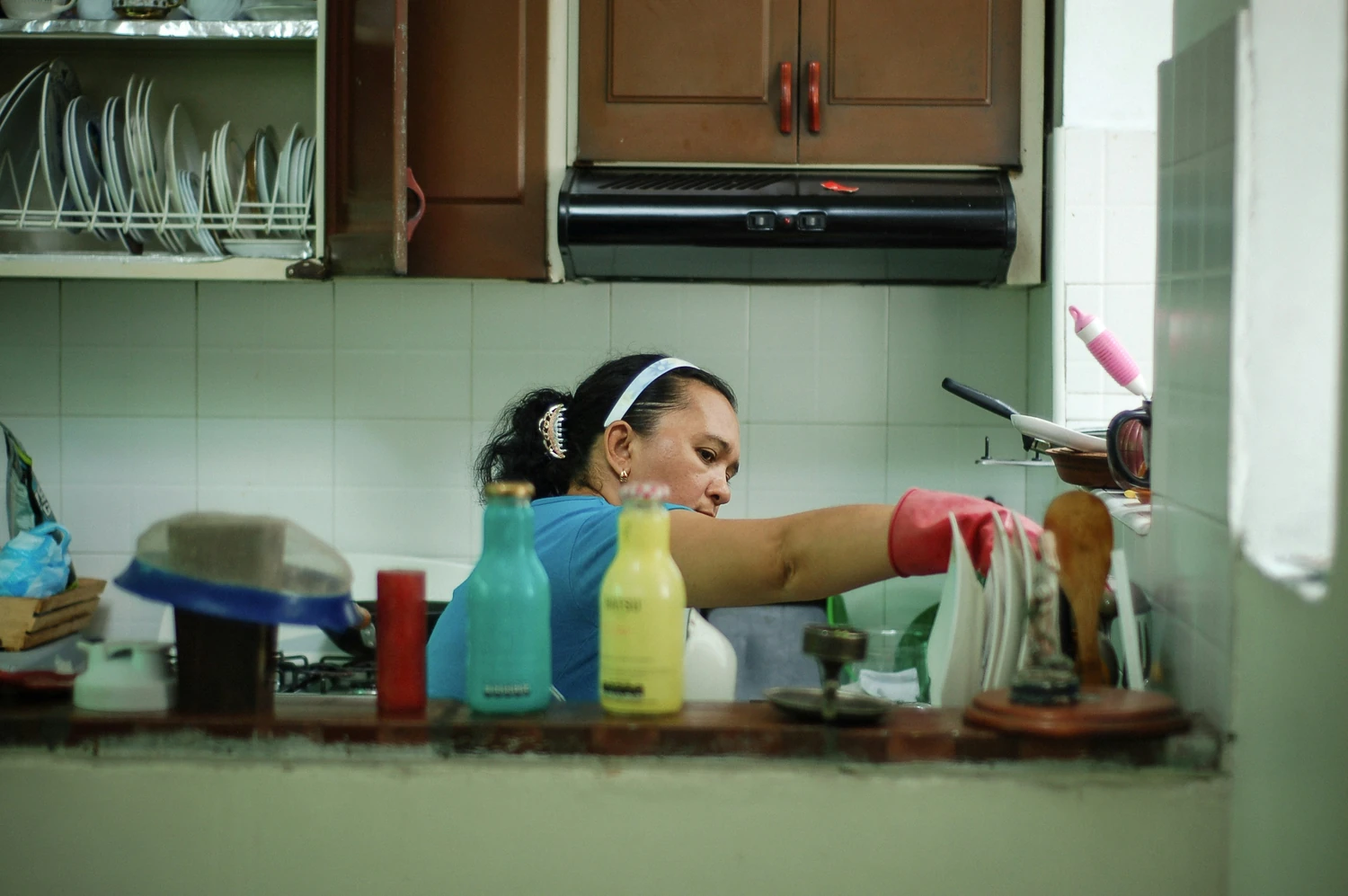 Housekeeper cleaning a kitchen with spray bottles and cloths