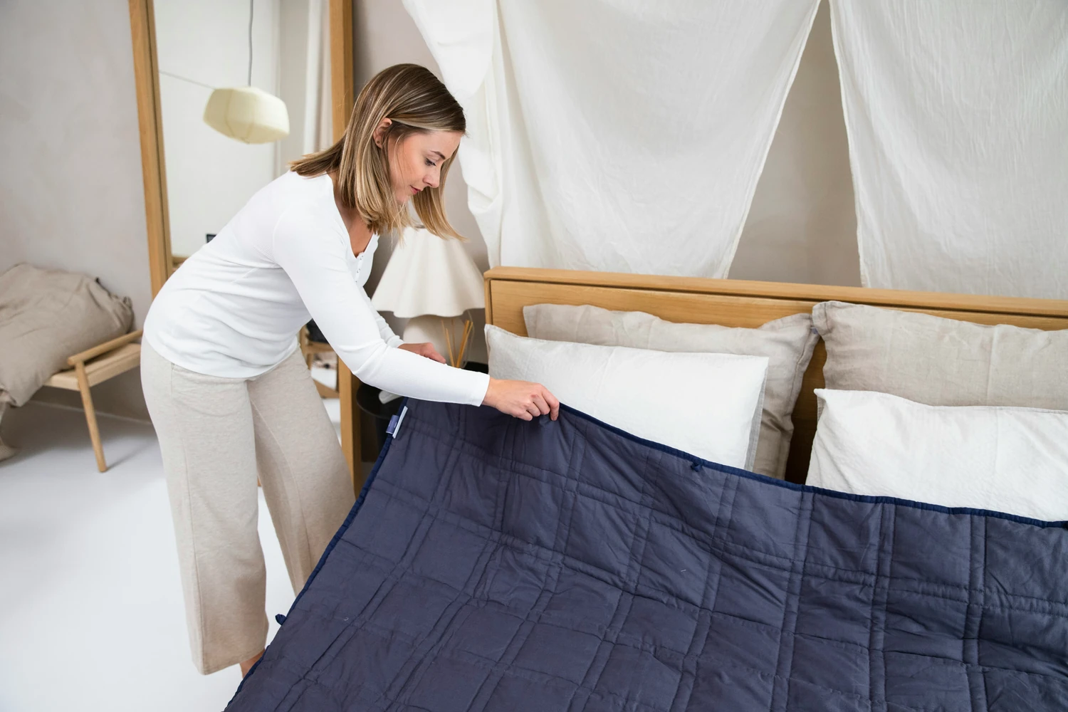 Housekeeper smoothing a dark blue blanket across a bed