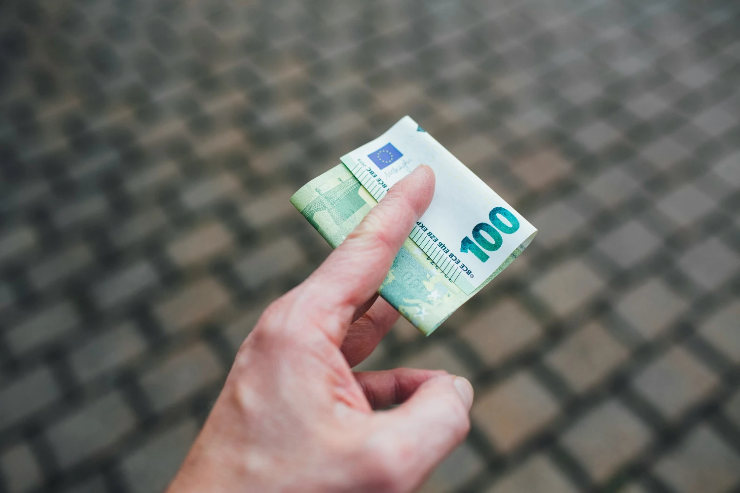 Hand holding a one-hundred-euro banknote