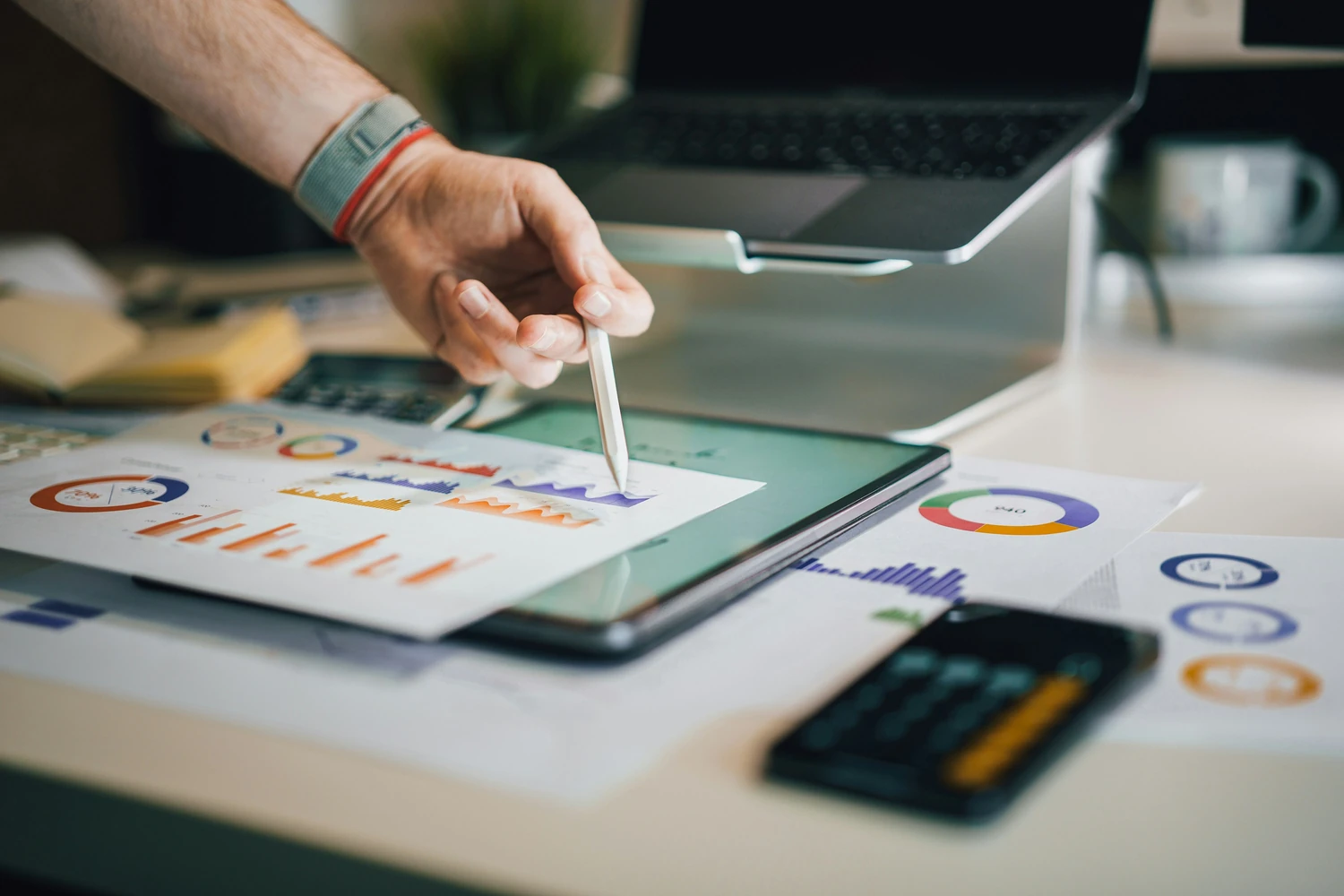 Person reviewing printed charts with a calculator and pencil