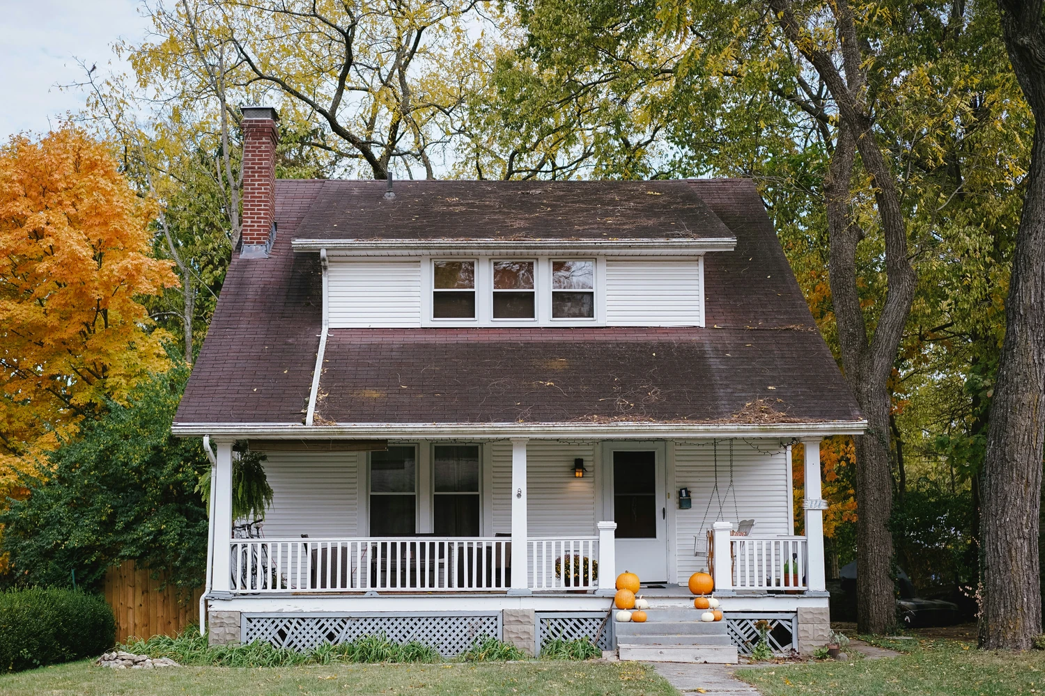 Small white house surrounded by autumn trees