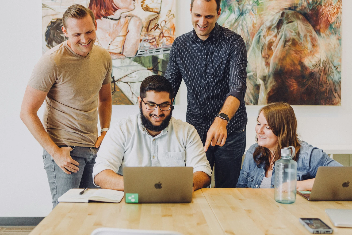 Four coworkers collaborating around a laptop