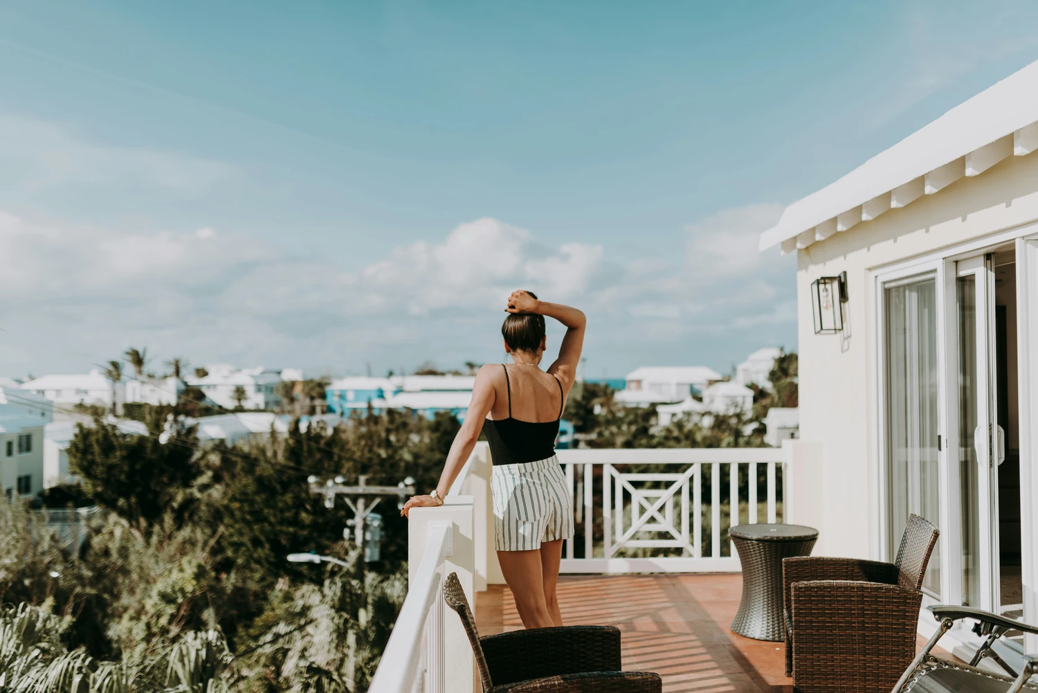 Woman using binoculars from a sunny vacation-home terrace