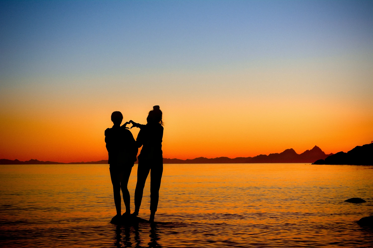 Couple standing together on a beach at sunset