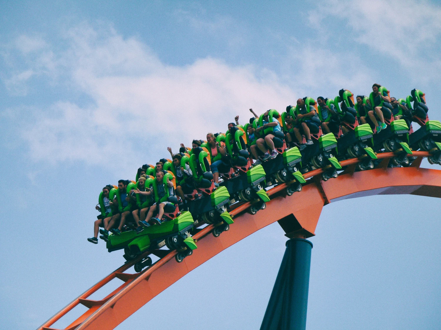 Vacationers riding a roller coaster beneath a blue sky