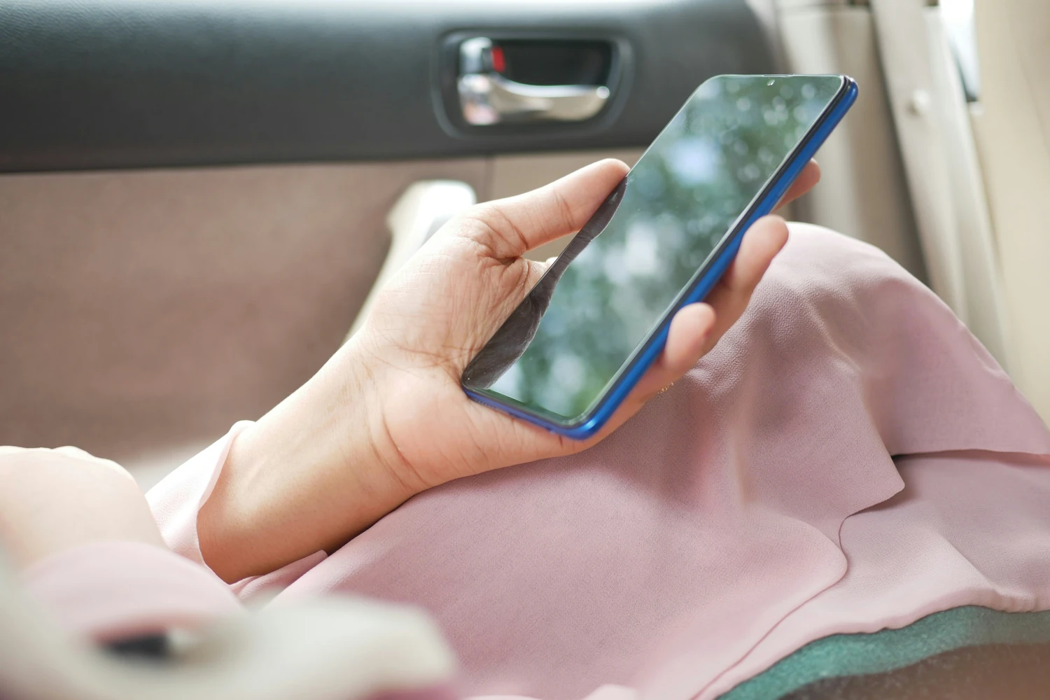 Person using a smartphone from inside a car