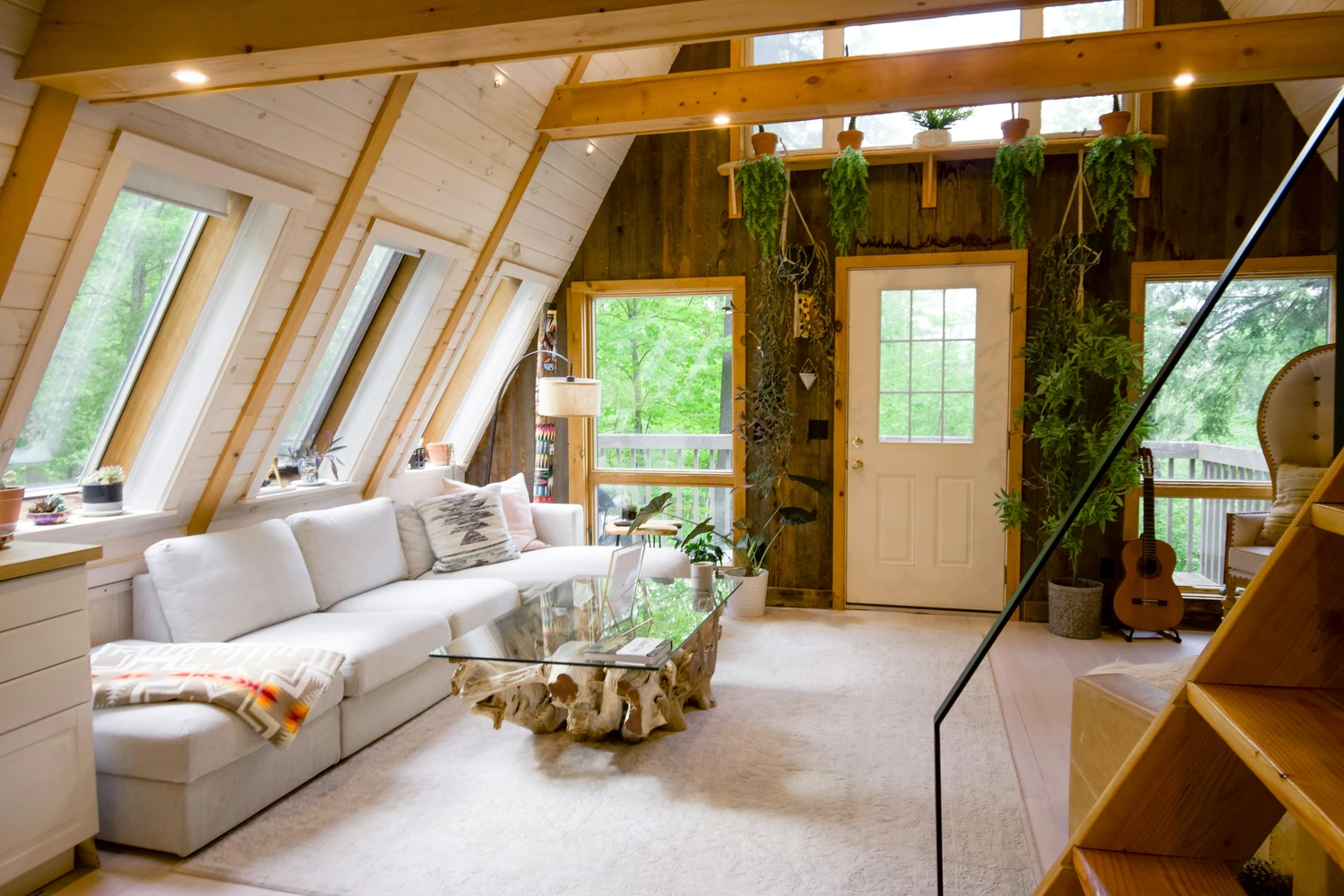Sunlit A-frame cabin interior with white sofas and wood paneling