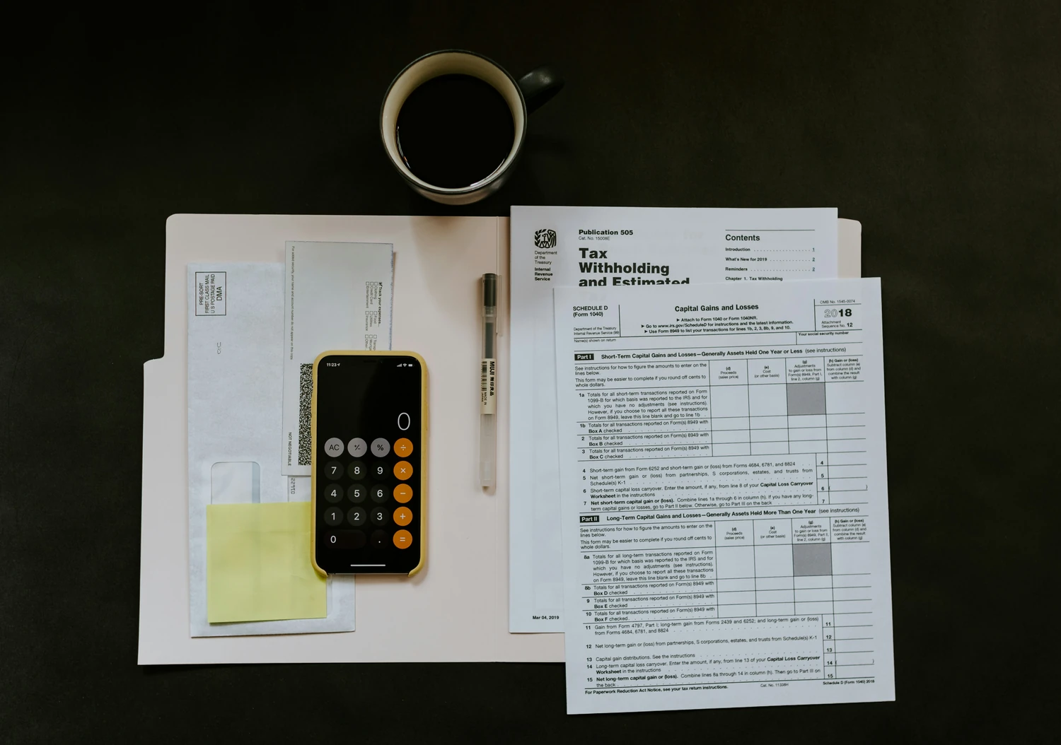 Tax documents, calculator, smartphone, and coffee arranged on a desk